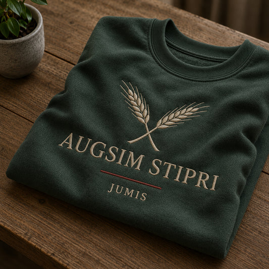 Meža zaļš salocīts džemperis ar “Augsim stipri” izšuvumu plašākā plakanā izkārtojuma kopskatā