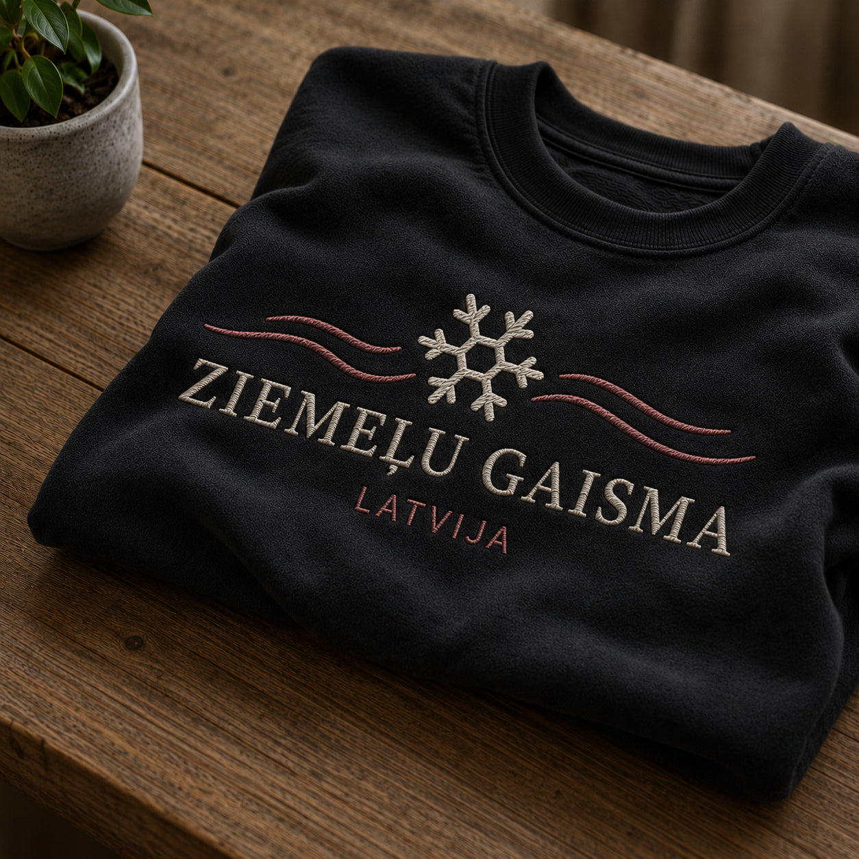 Melns salocīts džemperis ar “Ziemeļu gaisma” izšuvumu plašākā plakanā izkārtojuma kopskatā