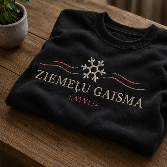 Melns salocīts džemperis ar “Ziemeļu gaisma” izšuvumu plašākā plakanā izkārtojuma kopskatā