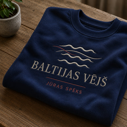 Tumši zils salocīts džemperis ar “Baltijas vējš” izšuvumu plašākā plakanā izkārtojuma kopskatā