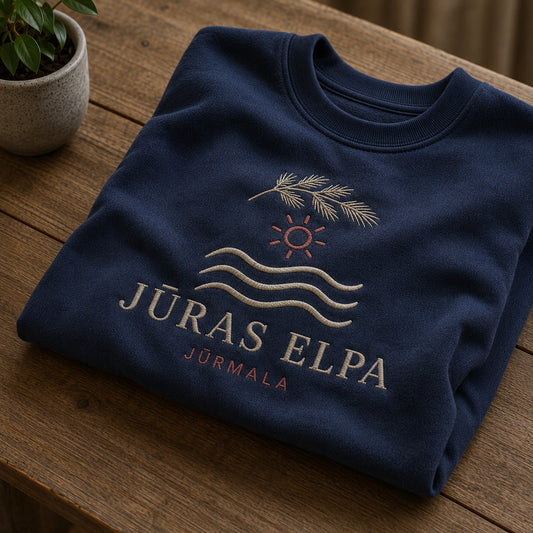 Tumši zils salocīts džemperis ar “Jūras elpa” izšuvumu plašākā plakanā izkārtojuma kopskatā