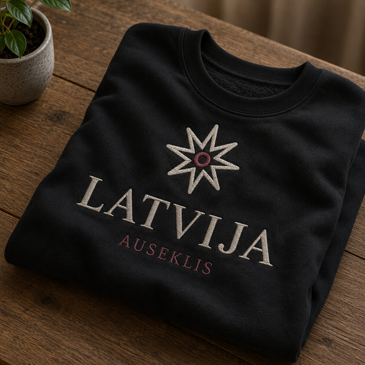 Melns salocīts džemperis ar “Auseklis Latvija” izšuvumu plašākā plakanā izkārtojuma kopskatā